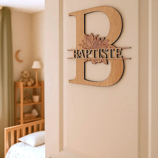 Monogramme en bois représentant la lettre B avec le prénom "Baptiste" et un motif floral de marguerites, fixé sur une porte de chambre d’enfant – décoration personnalisée élégante.